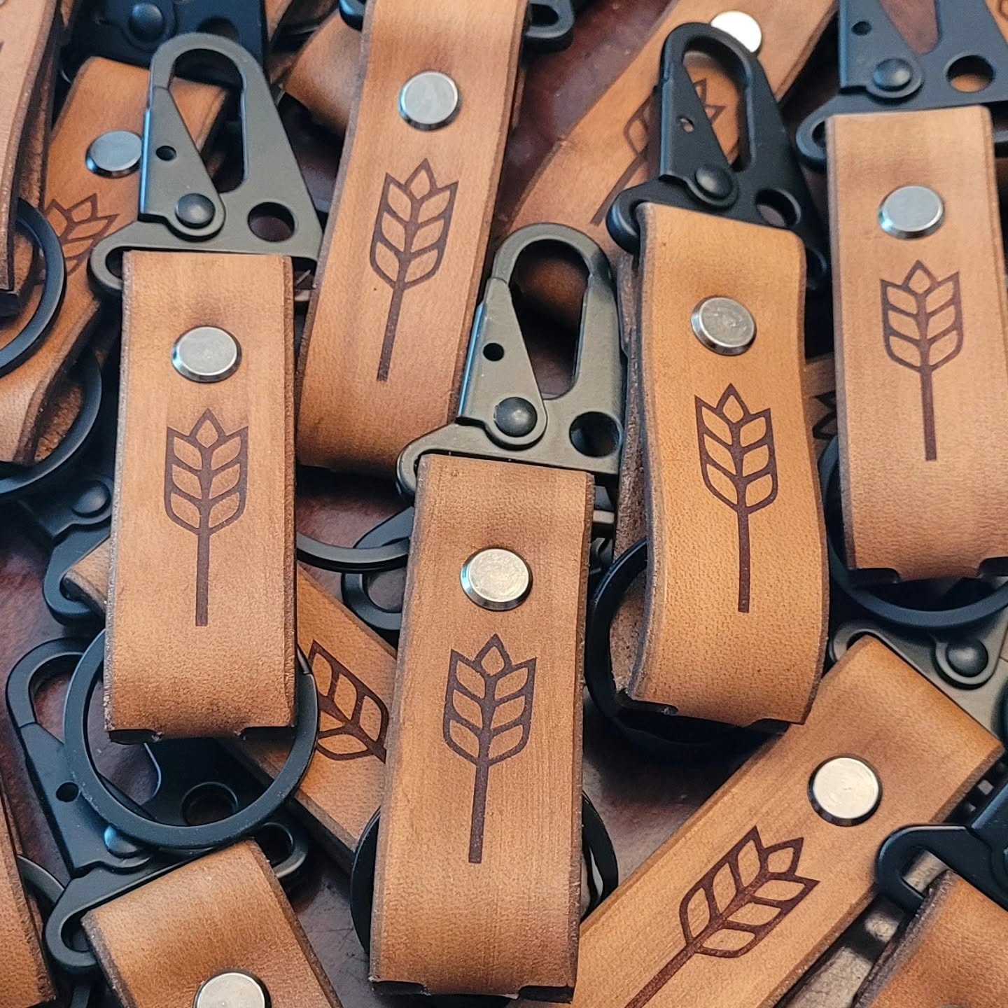 Leather keychains engraved with wheat logos and fitted with metal clips
