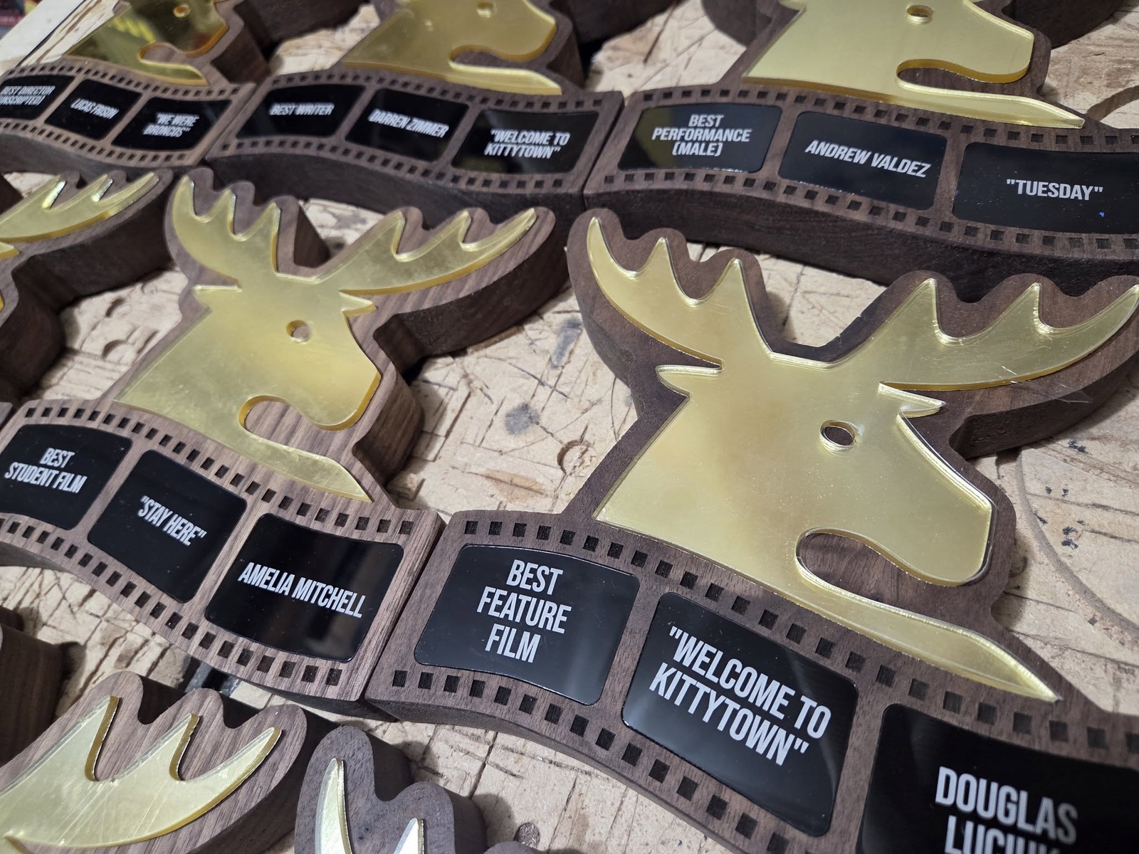 Custom Moose Jaw Film Festival awards with gold-coloured moose silhouettes, wooden bases and engraved filmstrip plaques