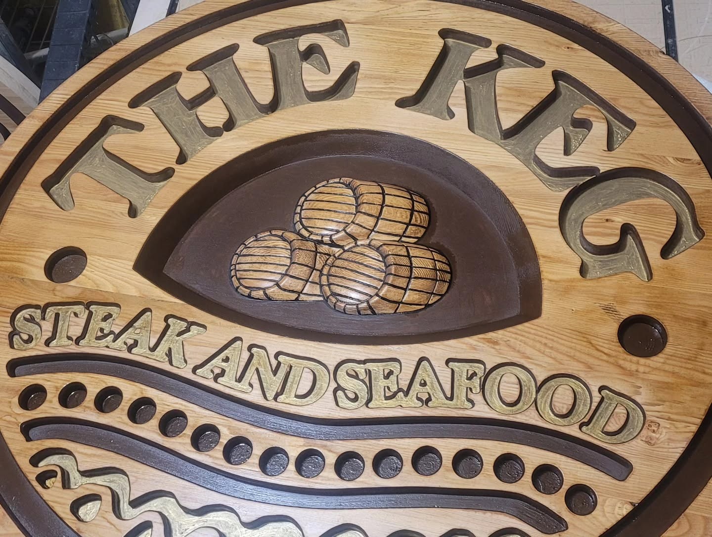 Close-up of large carved wood restaurant sign with keg relief artwork
