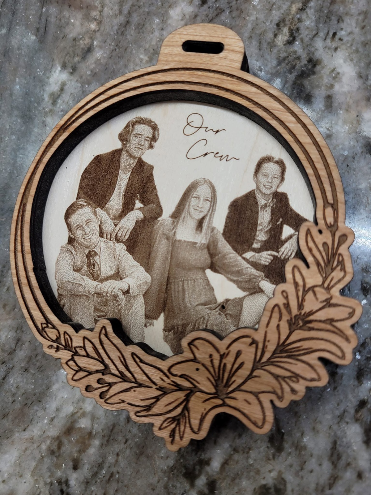 Layered wood ornament with an engraved group portrait and decorative leaf border